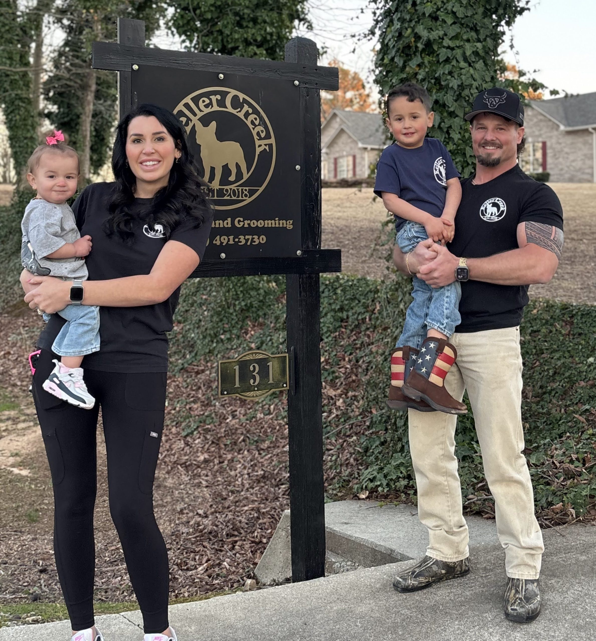 Tyson and Ashten Cash with children Taege and Janie standing in front of the Keller Creek sign